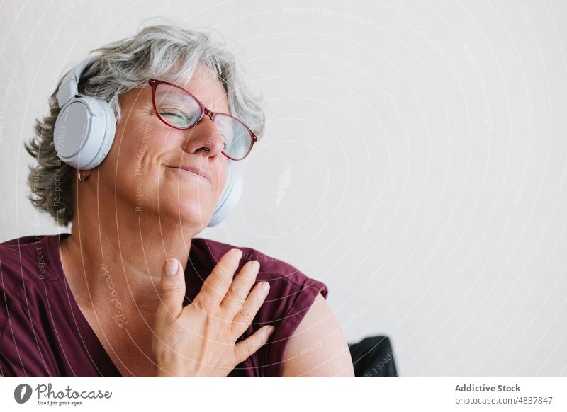 Zufriedene ältere Dame, die mit geschlossenen Augen über Kopfhörer Musik hört Frau zuhören Augen geschlossen meloman genießen Gesang Audio Inhalt positiv