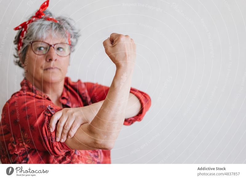 Ernste ältere Feministin zeigt Muskeln und schaut in die Kamera Frau zeigen Bizeps hochstecken Konzentration Stil so tun, als ob Kraft stark manifestieren