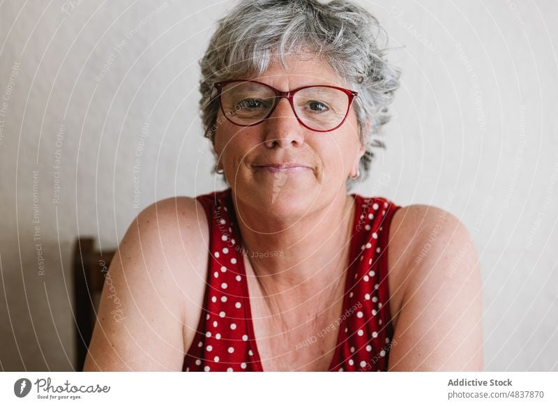Lächelnde ältere Frau zu Hause mit Blick in die Kamera Glück positiv Porträt froh Optimist Vorschein Persönlichkeit Stil heiter Senior graues Haar lässig Brille