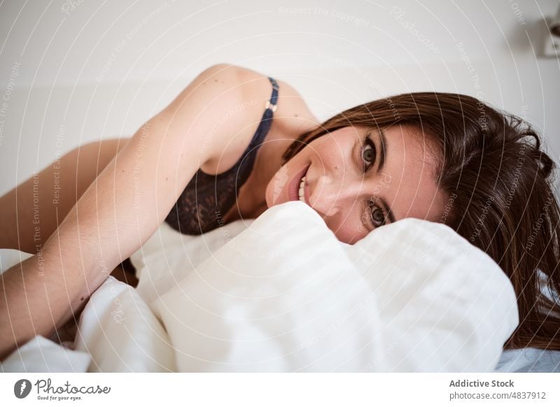 Fröhliche Frau in Dessous auf dem Bett liegend Unterwäsche sinnlich Verlockung verführerisch provokant feminin Schlafzimmer Spaß haben positiv froh Glück