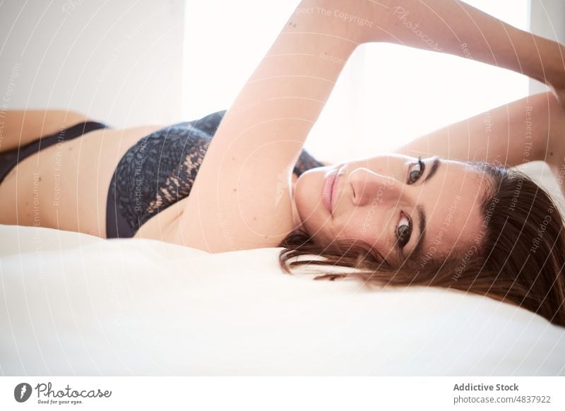 Glückliche Frau in Dessous auf dem Bett liegend Unterwäsche sinnlich Verlockung verführerisch provokant feminin Schlafzimmer Spaß haben positiv froh Optimist