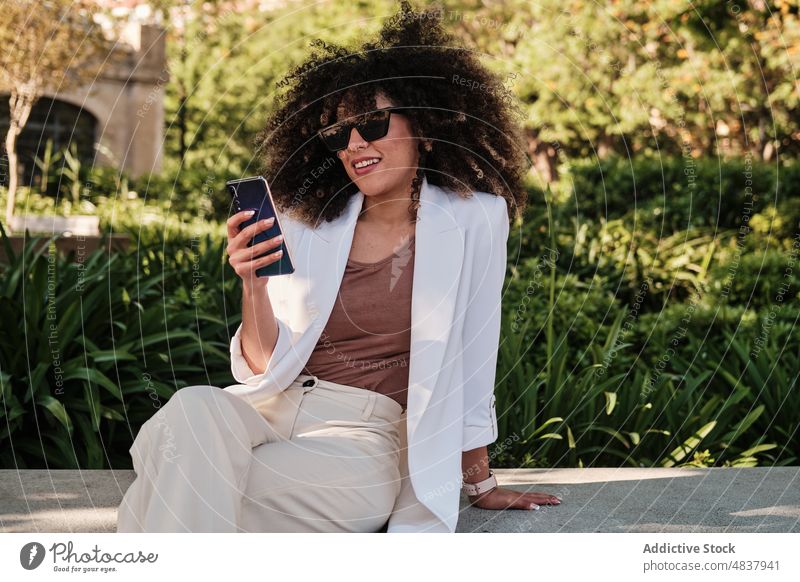 Hispanische Geschäftsfrau, die auf der Straße mit ihrem Handy surft Browsen Smartphone urban Frau Nachricht hispanisch ethnisch Sonnenbrille smart lässig Text