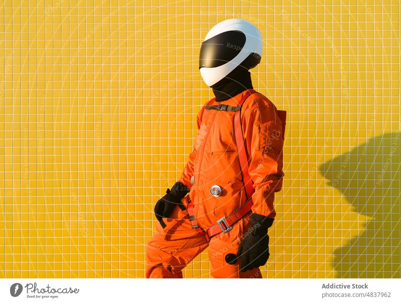 Selbstbewusster Kosmonaut vor gelber Wand Astronaut Raumanzug selbstbewusst Erfolg Tracht Konzept Sand Strand erkunden Uniform Schutzhelm Mut Sicherheit
