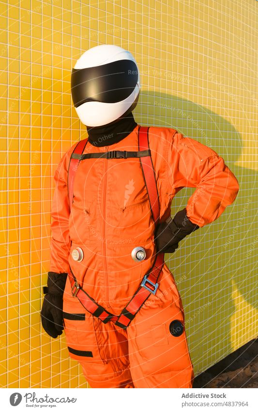 Selbstbewusster Kosmonaut vor gelber Wand Astronaut Raumanzug selbstbewusst Erfolg Tracht Konzept Sand Strand erkunden Uniform Schutzhelm Mut Sicherheit