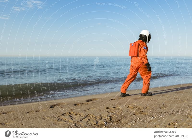 Raumfahrer, der spazieren geht und das Meer bewundert Strand MEER Astronaut bewundern Abend schlendern ruhen Konzept futuristisch Resort Sand Urlaub Spaziergang