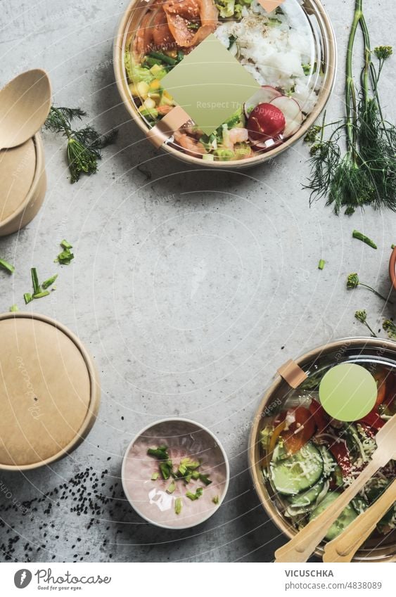 Gesunde Salate Mittagessen in nachhaltigen Verpackungen mit leeren Etikett Mock-up auf grauen Tisch Hintergrund mit Kräutern und biologisch abbaubare Lebensmittel-Container. Leckere Poke-Schalen zum Mitnehmen.