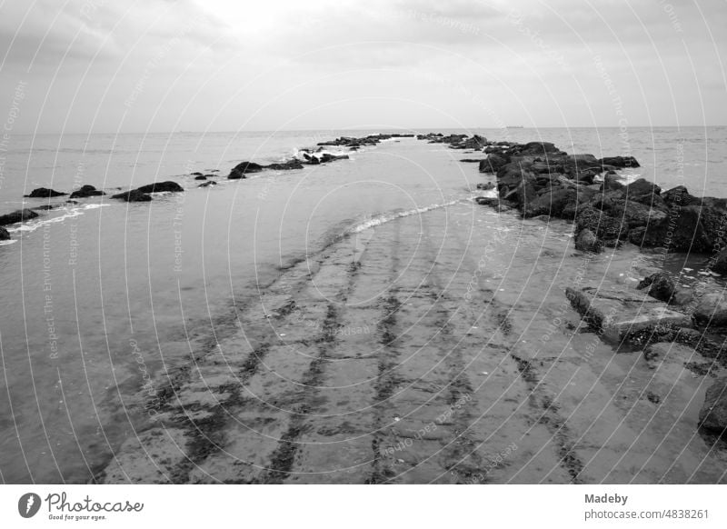 Steine und Mauerwerk als Wellenbrecher für den Küstenschutz bei Regenwetter am Strand in Knokke-Heist an der Nordsee bei Brügge in Westflandern in Belgien, fotografiert in klassischem Schwarzweiß