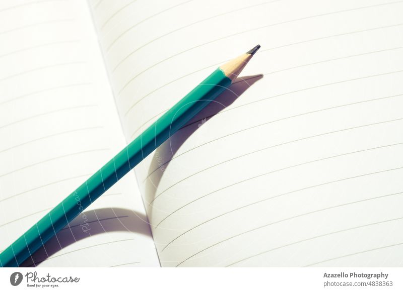 Aquablauer Bleistift auf einem offenen Notizbuch. Nahaufnahme eines Bleistifts auf weißem Papier. Notebook blanko abschließen Makro Minimalismus abstrakt hell