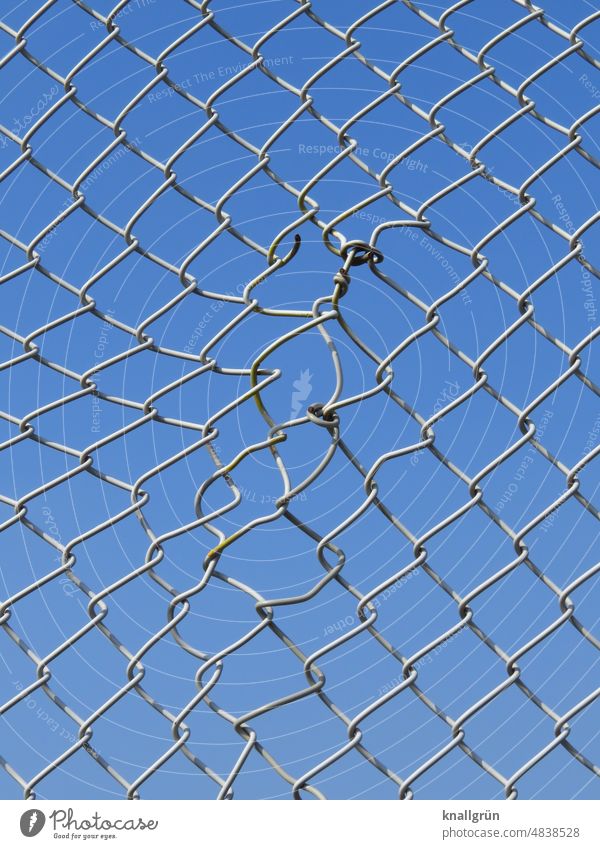Geflickter Maschendrahtzaun Schutz Sicherheit Zaun Barriere Grenze Drahtzaun Metall Außenaufnahme Menschenleer gefangen Detailaufnahme Himmel blau silber grau