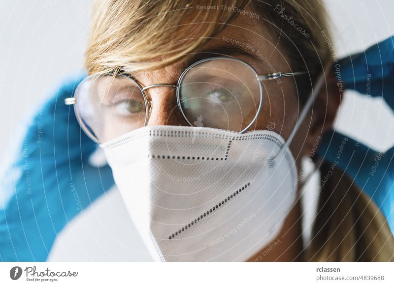 Frau trägt N95 FFP2, eine Schutzmaske gegen Viren, und die Brille ist beschlagen, um andere vor einer Infektion mit Corona COVID-19 und SARS cov 2 zu schützen