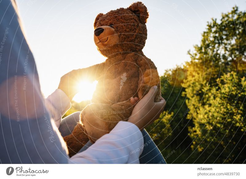 Frau hält Teddybär Spielzeug mit Sonnenlicht bei Sonnenuntergang Bär Rücken Erwachsener allein Weg Beteiligung schön traurig Schönheit Laufsteg Mädchen Körper