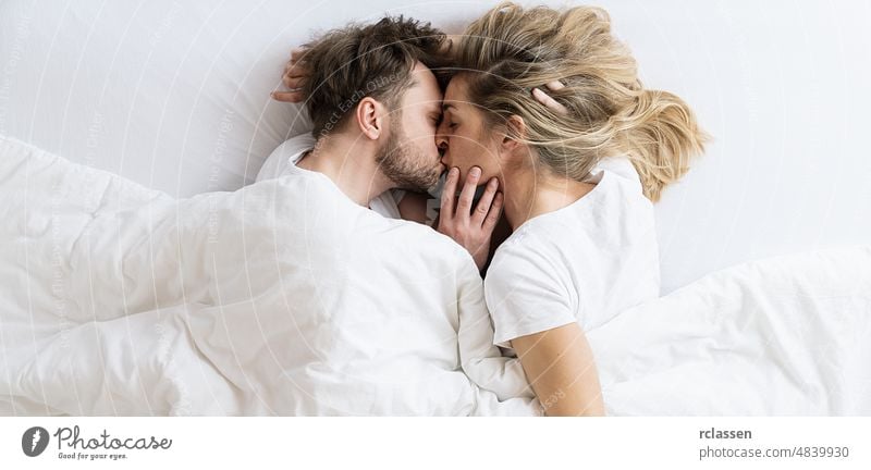 Liebesgeschichte. Paar küssen auf dem Bett liegend in einem hellen Raum am Morgen. Liebe, Glück, Familie. Draufsicht Schuss Sex sexy Mann Frau Kuss männlich