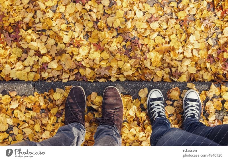 Junger Mann und seine Freundin stehen im Herbst auf einem Bordstein, Fußgänger- oder Flortrait aus hohem Winkel, persönliche Perspektive von oben. pov Menschen