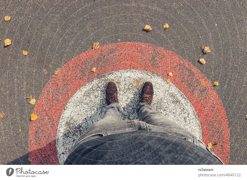 Junger Mann steht im Herbst in einem Kreis auf der Straße, persönliche Perspektive von oben. pov Menschen Lifestyle Punkt Ansicht Weg Kaukasier jung