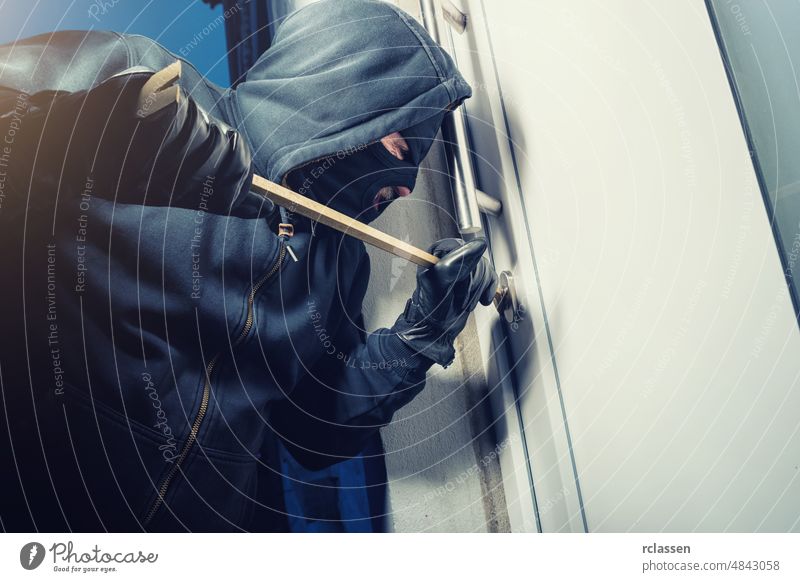 maskierter Einbrecher öffnet eine Tür mit einem Brecheisen Polizei Appartement stehlen weiß Überfall Werkzeug Hauseinbrecher Konzept Pause ungesetzlich männlich