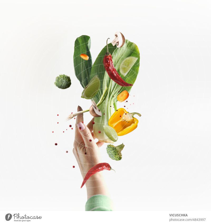 Fliegende vegetarische Lebensmittel Zutaten mit Frauen Hand auf weißem Hintergrund. Gemüse fliegen Vegetarier weißer Hintergrund Bockshornklee Pilze Paprika