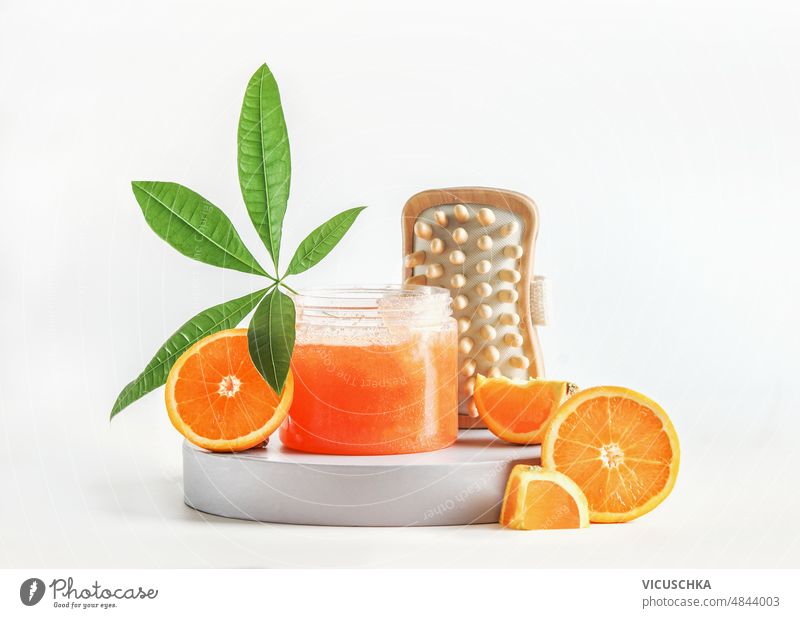 Körperpflege-Set mit Orangenzucker-Peeling, geschnittenen Orangen, grünem Blatt und Massagebürsten auf weißem Hintergrund. Einstellung orange Zuckerpeeling