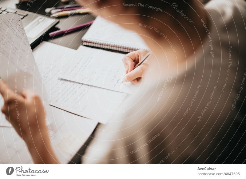 Close up Detailbild einer jungen Frau studieren und arbeiten auf seinem Schreibtisch zu Hause, Hausaufgaben während der Universität, die Vorbereitung für die Prüfung mit Lehrbuch und Notizen, selektiven Fokus auf den Bleistift.