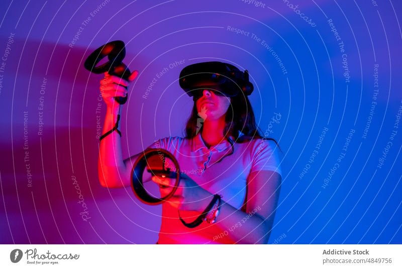 Frau mit VR-Headset beim Spielen eines Videospiels Cyberspace simulieren futuristisch Virtuelle Realität Spieler spielen erweitert modern erkunden neonfarbig