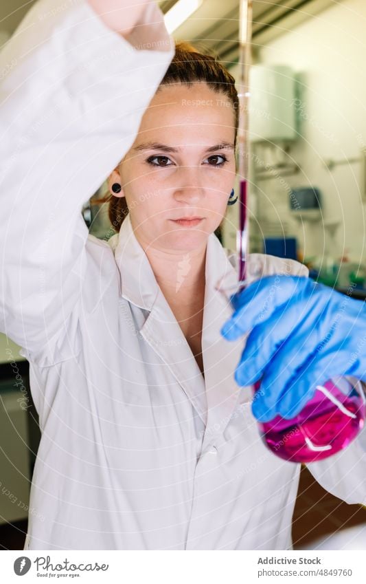 Chemiker gießt Flüssigkeit in Kolben im Labor Frau Wissenschaftler Chemikalie liquide eingießen Experiment Flasche Probe forschen Kompetenz Apotheke Fokus