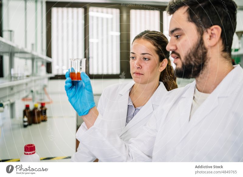 Chemiker bei der Untersuchung einer chemischen Flüssigkeit im Labor Wissenschaftler Kollege Chemikalie Probe forschen Humpen liquide untersuchen Prüfung