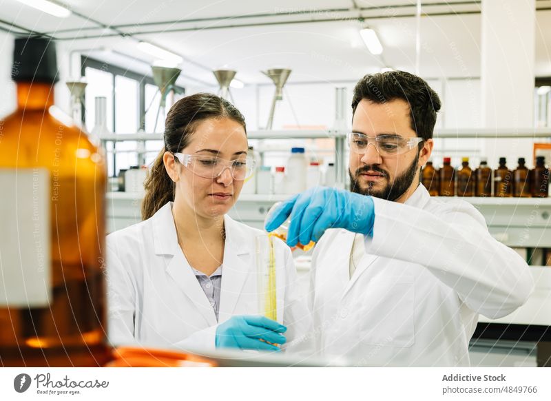Wissenschaftler gießen eine chemische Flüssigkeit in ein Reagenzglas Mitarbeiterin Labor Chemikalie eingießen Prüfung liquide Chemiker Kollege Experiment Probe