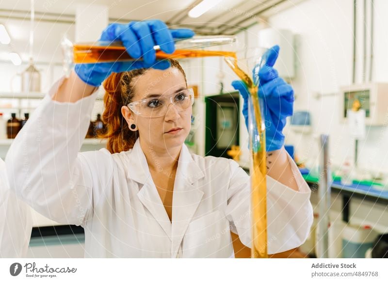 Konzentrierter Wissenschaftler, der eine chemische Flüssigkeit in ein Labor gießt Frau eingießen Chemikalie forschen Chemiker Experiment liquide Reagenzglas