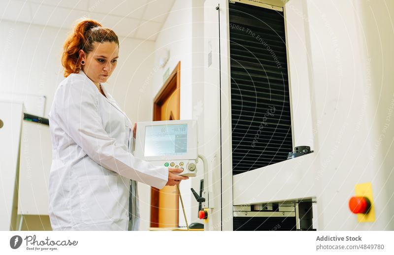 Frau beim Einrichten von Geräten im Labor Wissenschaftler einrichten Maschine Vorrichtung Anzeige wissenschaftlich System Fokus Arbeit professionell Uniform