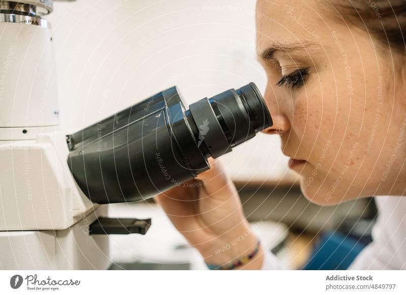 Fokussierter Wissenschaftler beim Blick durch das Mikroskop im Labor Frau untersuchen Chemiker forschen analysieren wissenschaftlich Experiment Kompetenz Arbeit