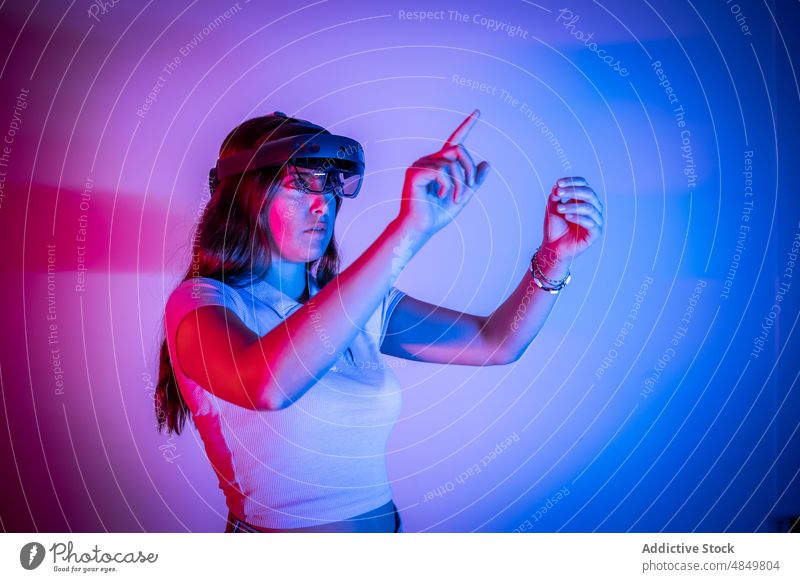 Frau mit VR-Headset beim Spielen eines Videospiels Cyberspace simulieren futuristisch Virtuelle Realität Spieler spielen erweitert modern erkunden neonfarbig