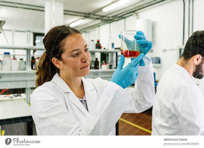 Seriöser Chemiker, der eine Flüssigkeit in einem Kolben im Labor untersucht Frau Wissenschaftler Flasche liquide untersuchen wissenschaftlich Chemikalie