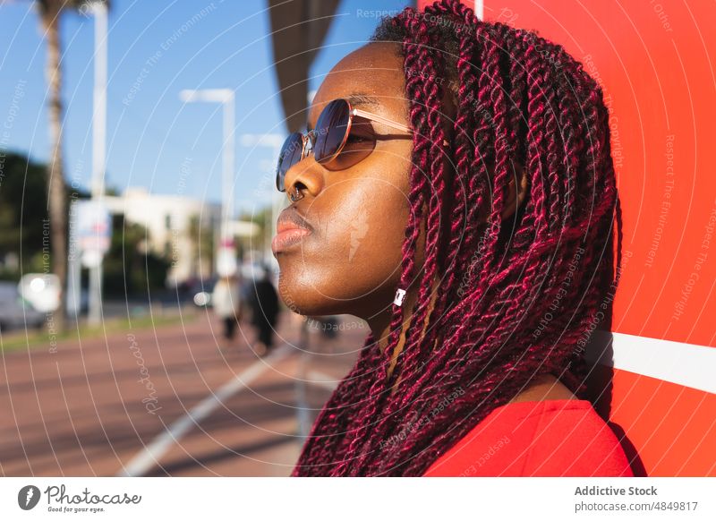 Seriöse junge schwarze Frau in trendigem Outfit Afrikanisch Porträt trendy Stil Sonnenbrille Afroamerikaner rot Wand sonnig ernst modern selbstbewusst Mode