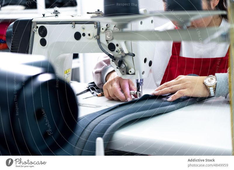 Gesichtslose Näherin an der Nähmaschine in einer Fabrik Damenschneiderin Textil nähen Werkstatt Herstellung Industrie Inszenierung Arbeit Instrument Vorrat