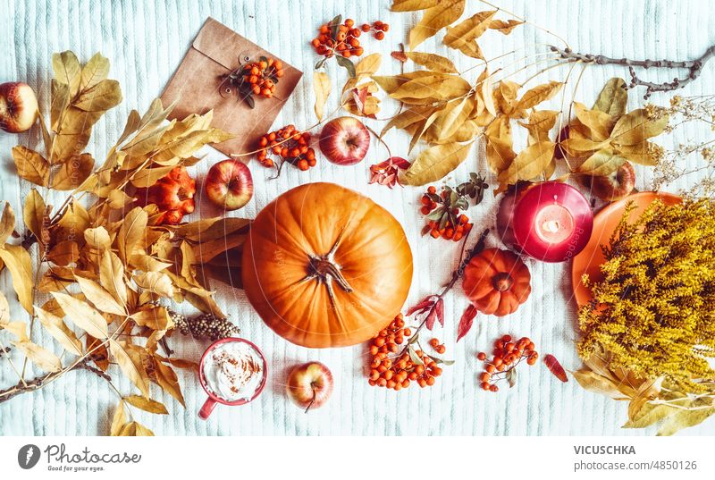 Herbstlicher Lifestyle mit Kürbis, Briefumschlag, gelben Herbstblättern, heißer Schokoladentasse, Kerzen und Äpfeln Kuvert Herbstlaub Kakao Tasse weiß Decke