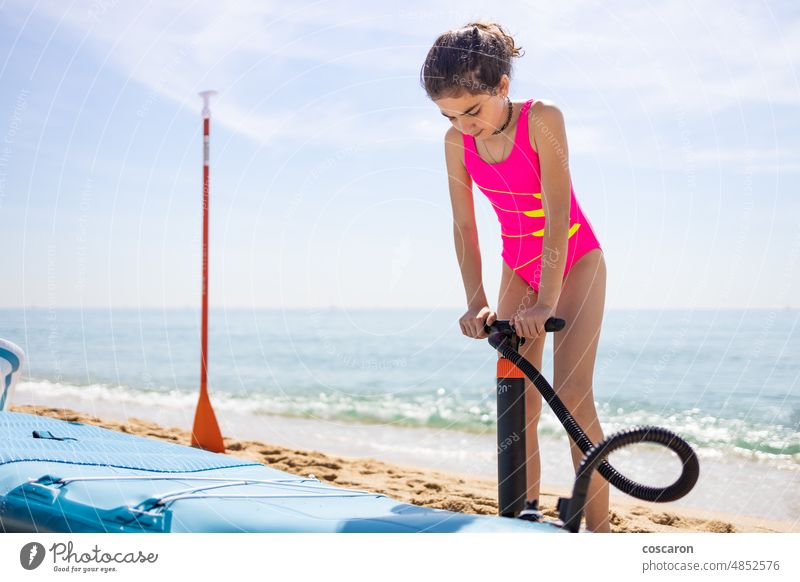 Kleines Mädchen bläst ein Surfpaddel am Strand auf aktiv Aktivität Abenteuer Gleichgewicht Holzplatte Boarding Kind Kindheit Übung Familie Freunde Spaß Glück
