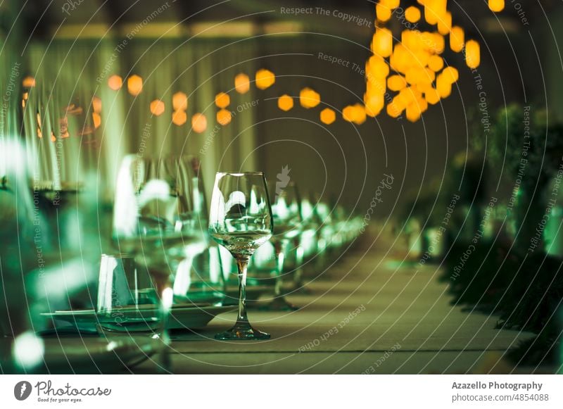 Blick auf den Hochzeitstisch mit verschwommenen gelben Lichtern. Wein Glas Champagne Tisch Festessen Feier abstrakt grün seicht Tiefe Feld Fokus Abend