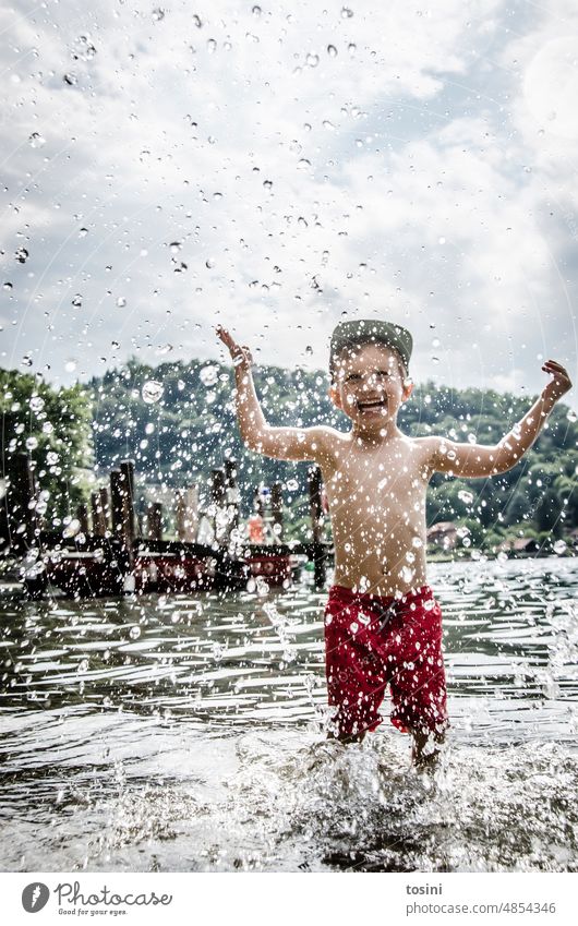 Kind steht im Wasser und spritzt mit Wasser Wassertropfen Spielen abkühlen spritzen Sommer Erfrischung Schwimmen & Baden Ferien & Urlaub & Reisen Außenaufnahme