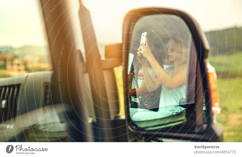 Reflexion im Rückspiegel eines Wohnmobils einer Frau, die ein Foto mit ihrem Handy macht Reflexion & Spiegelung unter Bild Freund fahren Mann Mobile