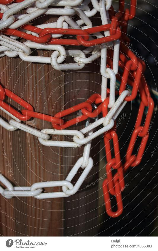 rot-weiße Absperrkette hängt an einem Holzpfahl Kette Pfahl hängen braun Kettenglieder Farbfoto Außenaufnahme Sicherheit Absperrung Strukturen & Formen
