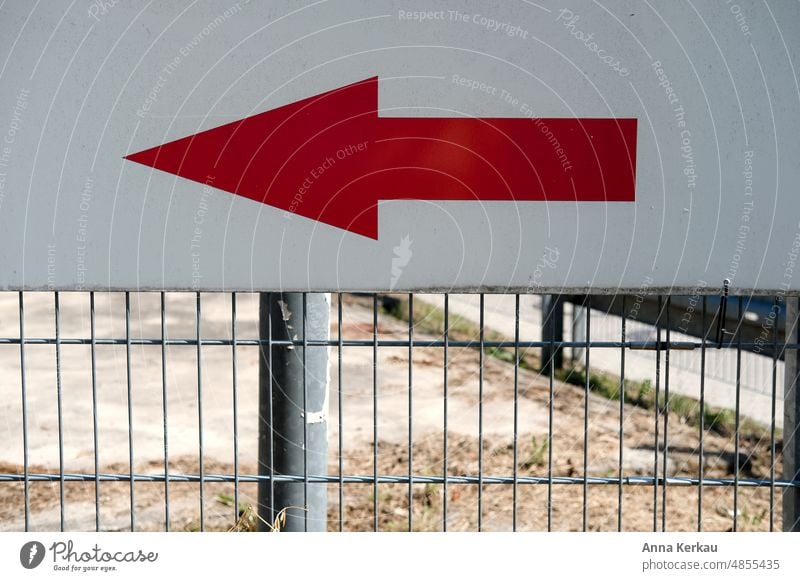 Links lang-ein roter Pfeil, der an einem Metallgitter befestigt ist, weist den Weg Hinweisschild in eine bestimmte Richtung rot-weiß richtungsweisend Linkspfeil