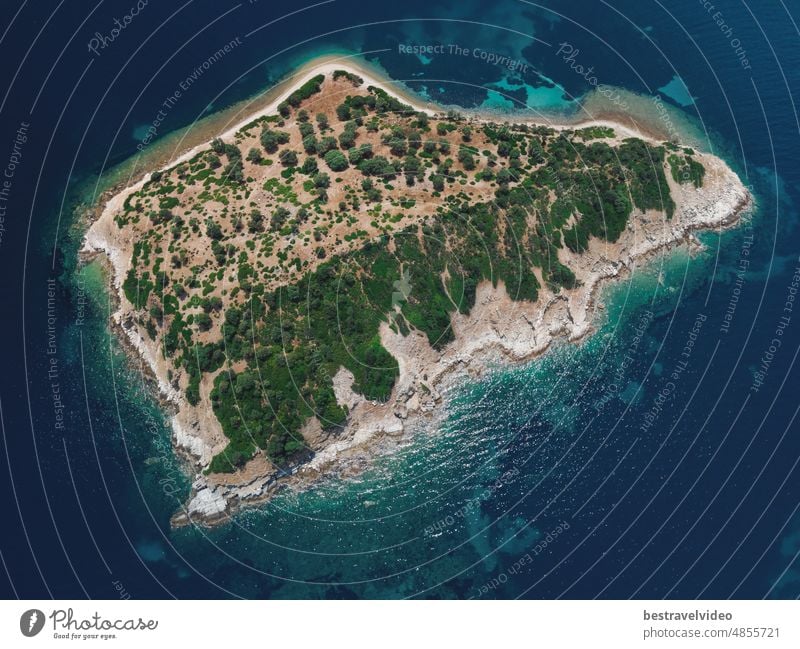 Drohnenansicht eines kleinen Inselstreifens mit grüner Vegetation und felsiger Küste im Mittelmeer auf der Halbinsel Chalkidiki, Griechenland.