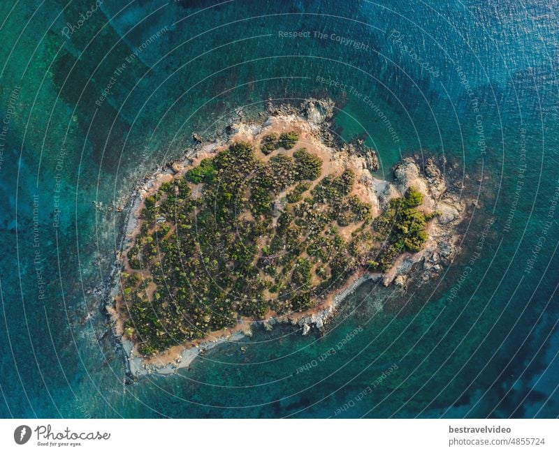 Tagesdrohnenansicht über einer kleinen Insel mit grüner Vegetation und felsiger Küste im Mittelmeer auf der Halbinsel Chalkidiki, Griechenland