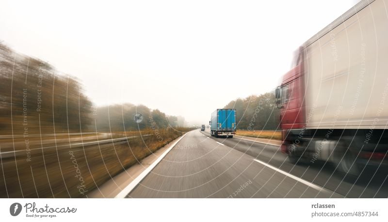 Lastwagen auf der Autobahn, die in einer nebligen Herbstlandschaft dem Horizont entgegenfahren, mit Platz für Ihren individuellen Text. PKW Straße Motor