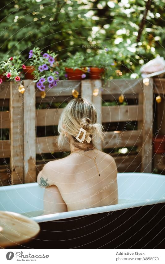 Unbekannte Frau sitzt in der Badewanne Wasser patio Hautpflege Terrasse Wohlbefinden Routine oben ohne Kälte Stil Vorschein Kübel ruhen Waschen Sommer charmant