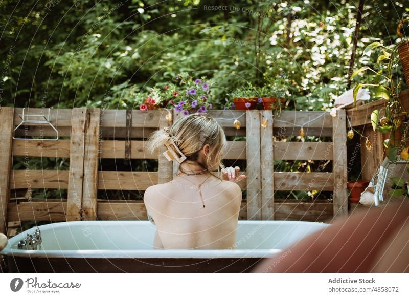 Unbekannte Frau sitzt in der Badewanne Wasser patio Hautpflege Terrasse Wohlbefinden Routine oben ohne Kälte Stil Vorschein Kübel ruhen Waschen Sommer charmant