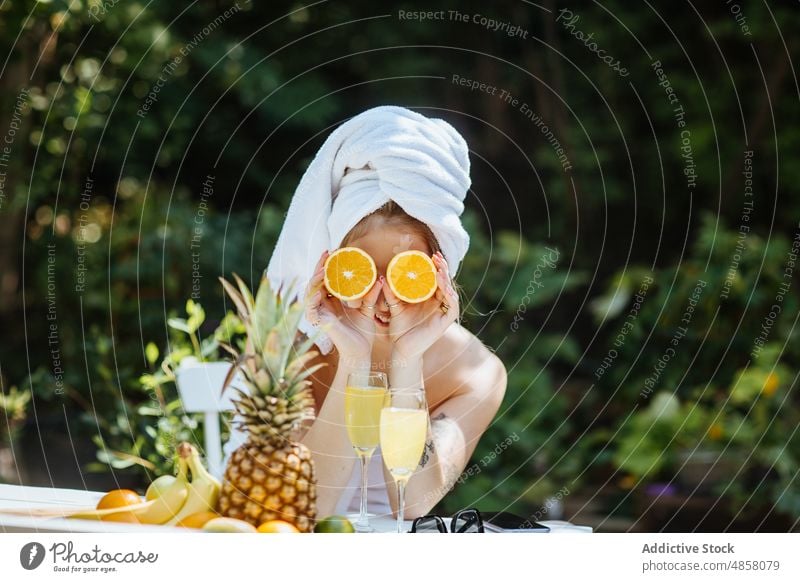 Frau bedeckt Augen mit Orangen auf Terrasse Handtuch Morgen patio Frucht orange Augen abdecken Frühstück Zitrusfrüchte Saft Getränk trinken feminin Sommer Glas