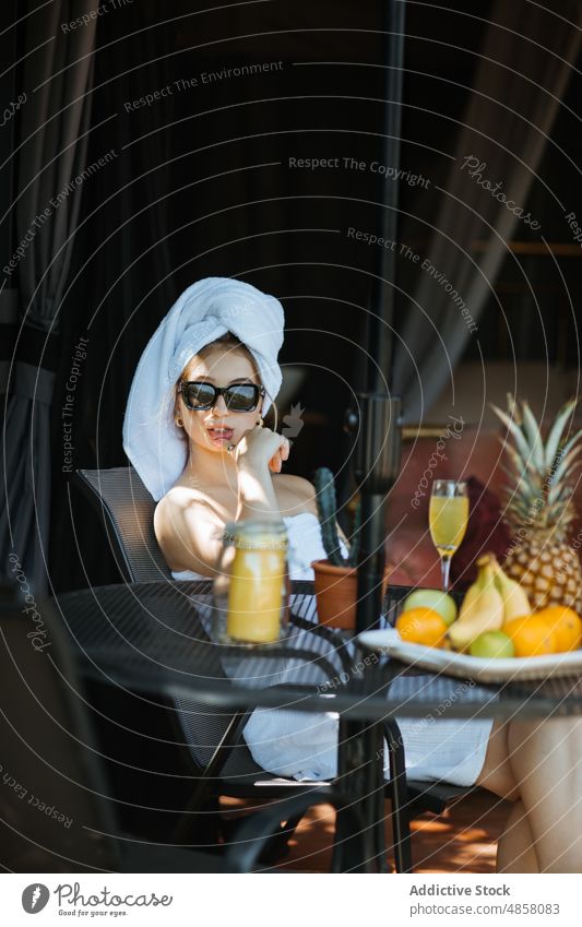 Frau in Handtüchern auf Terrasse sitzend Handtuch Morgen patio Literatur Hobby Zeitvertreib Gelassenheit Freizeit Saft Getränk trinken feminin Sommer Glas Tisch