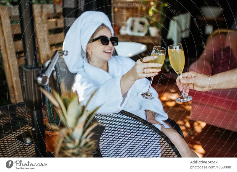 Frau im Handtuch stößt mit einer gesichtslosen Person auf ein Glas Saft an Terrasse patio Morgen Klirren Zuprosten Getränk trinken Erfrischung feminin Freizeit