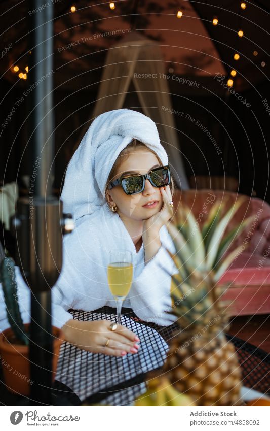 Frau in Handtüchern trinkt Cocktail auf Terrasse Handtuch Morgen patio Hobby Freizeit Saft Getränk trinken feminin Sommer Glas Tisch Sonnenbrille Stil