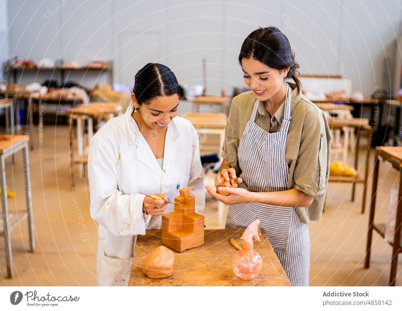 Fröhliche hispanische Frauen arbeiten gemeinsam mit Ton Kunstgewerbler Töpferwaren Zusammensein kreieren Geometrie Form Freundin Lächeln Kleinunternehmen jung